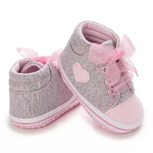 Detail of baby soft sole sneakers with pink polka dots and silk bow laces.