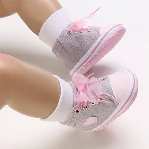 Dettaglio di scarpine neonato rosa a pois con fiocchi e suola morbida antiscivolo