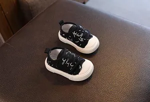 Vista detallada de zapatos de lona negros para bebé con patrones blancos y suelas antideslizantes