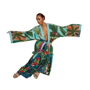 Dettaglio di un lungo kimono con stampa a foglie tropicali, motivi floreali e ampie maniche