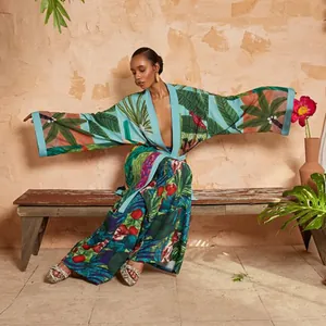Donna elegante in kimono con stampa a foglie tropicali seduta su panca rustica