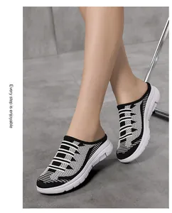 Close-up of breathable black and white fly-knit mesh slip-on mules on model feet.