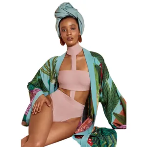 Dettaglio di un kimono con stampa tropicale e un bikini rosa a vita alta coordinato.