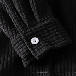 Macro close-up of a black waffle knit long-sleeve shirt cuff with a white button detail