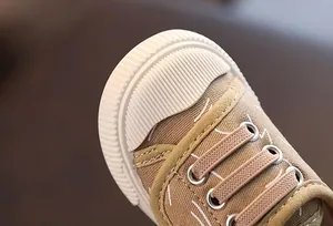 Detalle macro de zapato de lona para niños con puntera de goma y cordones elásticos
