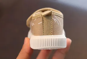 Vista detallada del talón reforzado de estos zapatos de lona beige para niños pequeños.