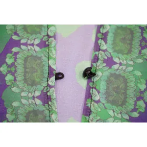 Nahaufnahme des Knopfverschlusses an bedrucktem lila und grünem Chiffonstoff-Detail