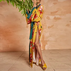 Elegante vestaglia kimono a fiori giallo senape con bordo verde acqua in ambiente ricercato.