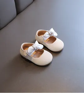 Nahaufnahme eleganter cremefarbener Baby-Prinzessinenschuhe mit weicher Sohle und Satinschleife