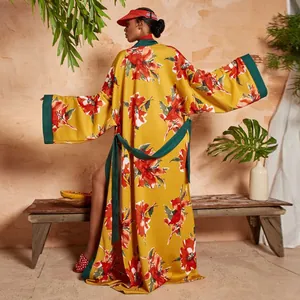 Dettaglio di un lungo kimono giallo a fiori con eleganti bordi verde scuro e cintura