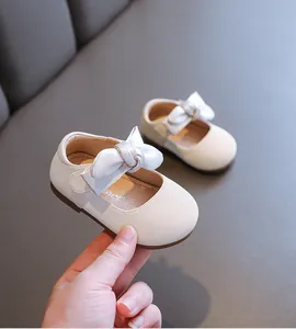 Nahaufnahme von cremefarbenen Baby-Prinzessin-Schuhen mit Satinschleife und weicher Sohle