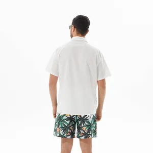 Back view of a white short sleeve shirt and tropical palm tree print beach shorts set