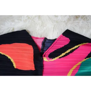 Detalle de vestido plisado de colores con escote en V y cierre de cremallera negro