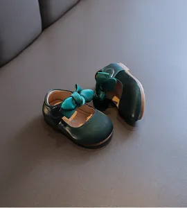 Detailaufnahme von dunkelgrünen Satin-Babyschuhen mit dekorativen Schleifen für Mädchen