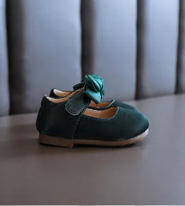 Nahaufnahme von dunkelgrünen Baby-Prinzessinenschuhen mit Schleife und weicher Sohle