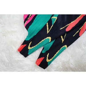 Detalle de cerca de la tela plisada con estampado abstracto y puños del vestido.