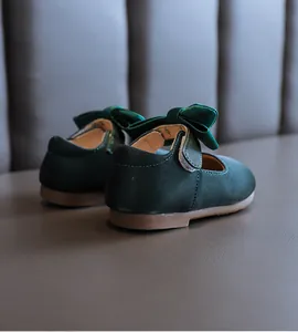 Nahaufnahme von dunkelgrünen Baby-Mary-Jane-Schuhen mit Schleife und weicher Sohle.