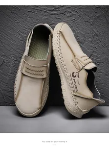 Detailopname van beige handgemaakte leren loafers met stiksels en een sportlogo