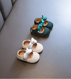 Nahaufnahme von Baby-Prinzessinnen-Schuhen mit Schleifen in Creme und Dunkelgrün.