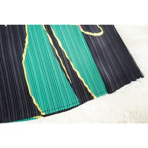 Primer plano de detalle de tela plisada con patrón verde y negro para vestido