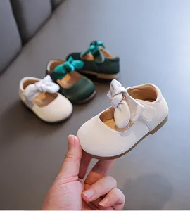 Nahaufnahme von weißen Baby-Prinzessinenschuhen mit einer weichen Schleife und Sohle