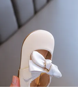 Detailaufnahme von weichen cremefarbenen Baby-Prinzessin-Schuhen mit großer Schleife