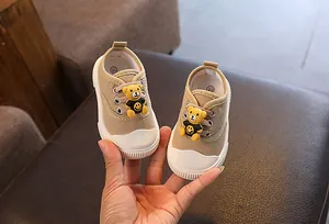 Detailansicht khakifarbener Baby-Stoffschuhe mit süßem Bären-Dekor und weißen Gummisohlen