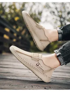 Close-up van beige heren loafers met handgestikte details en sport power logo print.
