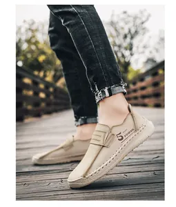 Detailopname van kaki herenloafers met handgestikte naden en een sportief zijlogo.