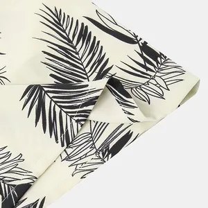 Detail view of tropical black palm leaf print on a white summer beach shirt fabric