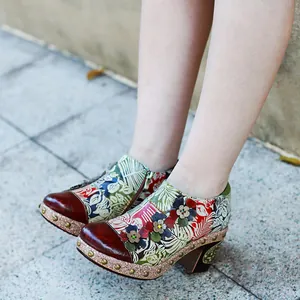 Close-up of vintage leather high heels with colorful floral patterns and 3D flower details.