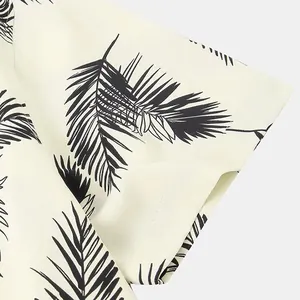 Detailed macro view of black palm leaf print on cream men's short sleeve Hawaiian beach shirt