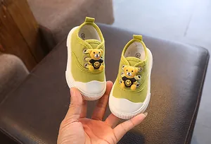 Detailansicht der niedlichen grünen Baby-Canvas-Schuhe mit 3D-Bären-Cartoon-Ornament.