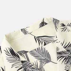 Detailed close-up showing the palm leaf print and lapel collar of a men's Hawaiian shirt.