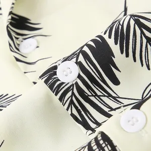 Macro detail showing the palm leaf print fabric and buttons of a Hawaiian beach shirt.