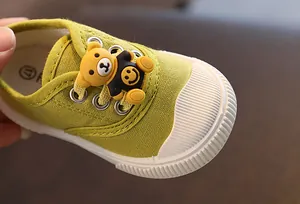 Nahaufnahme von grünen Baby-Segeltuchschuhen mit süßem Cartoon-Bär-Dekorationsdetail