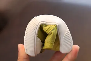 Nahaufnahme der flexiblen und weichen weißen Sohle grüner Baby-Canvas-Lauflernschuhe