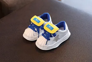 Detailed close-up of white toddler sneakers featuring a shell toe and star motif
