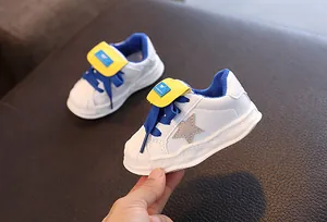 Close-up of children's white leather sneakers featuring shell toe and blue accents.