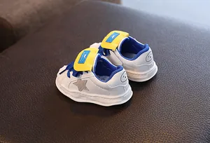 Close-up detail of white leather kids sneakers with star patch and yellow velcro strap