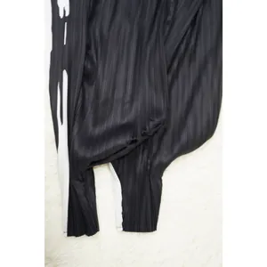 Primer plano de la tela plisada negra y el detalle de la raya blanca en el vestido.