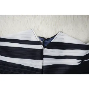 Primer plano de un vestido plisado a rayas blancas y negras con detalle de cuello en V