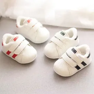 Dettaglio di scarpe da camminata per neonati foderate in peluche con strisce rosse e nere