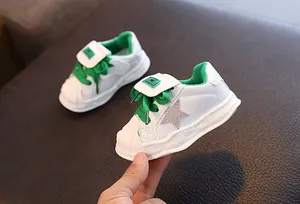 Close-up of white children's shell-toe sneakers with green laces and star detail