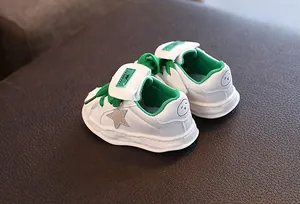 Detailed view of white leather children's sneakers with star design and green accents.