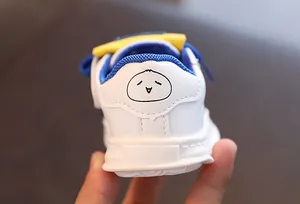 Macro view of cartoon chick pattern on white leather children's sneakers heel