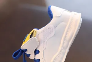 Close-up of premium white leather toddler sneakers with blue Velcro strap and laces