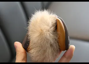 Nahaufnahme des weichen Kaninchenfell-Pompons an braunen Leder-Mokassins für Mädchen