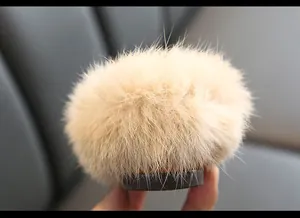 Nahaufnahme des weichen beigen Kaninchenfell-Pompons an den Kinderschuhen aus Leder