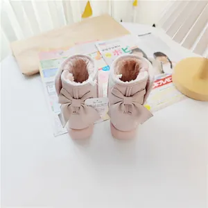 Detailed view of pink children's winter snow boots featuring elegant rear bow accents.